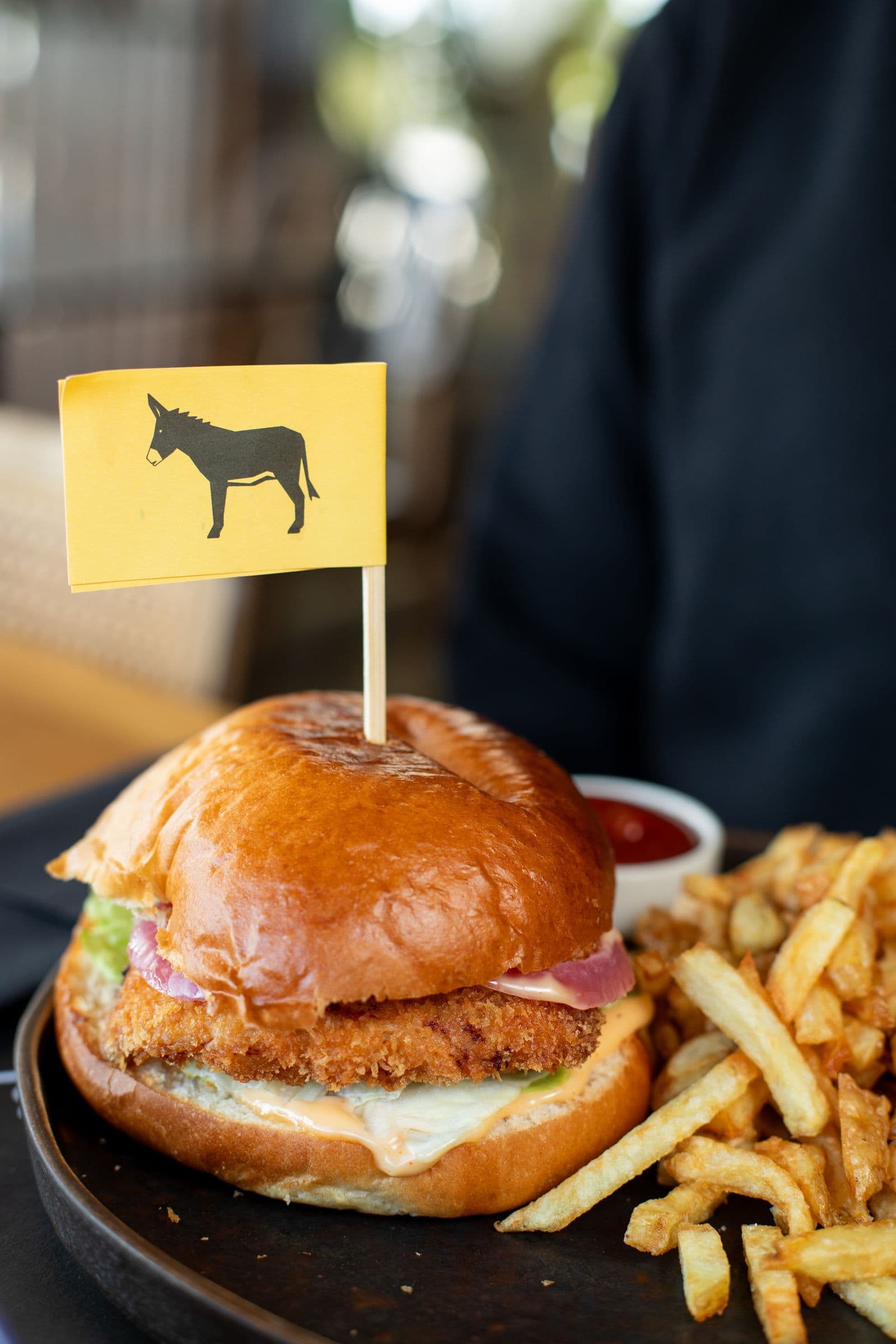 Fried Chicken burger on a brioche bun with a yellow donkey flag and French fries