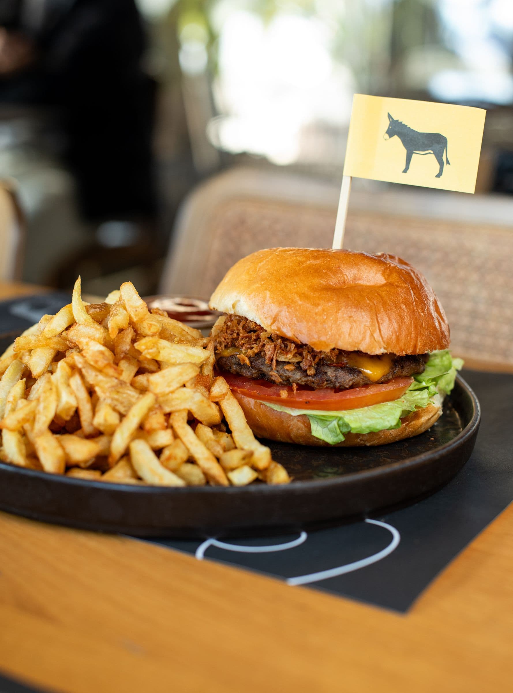 Black Angus beef burger with a yellow donkey flag and French fries