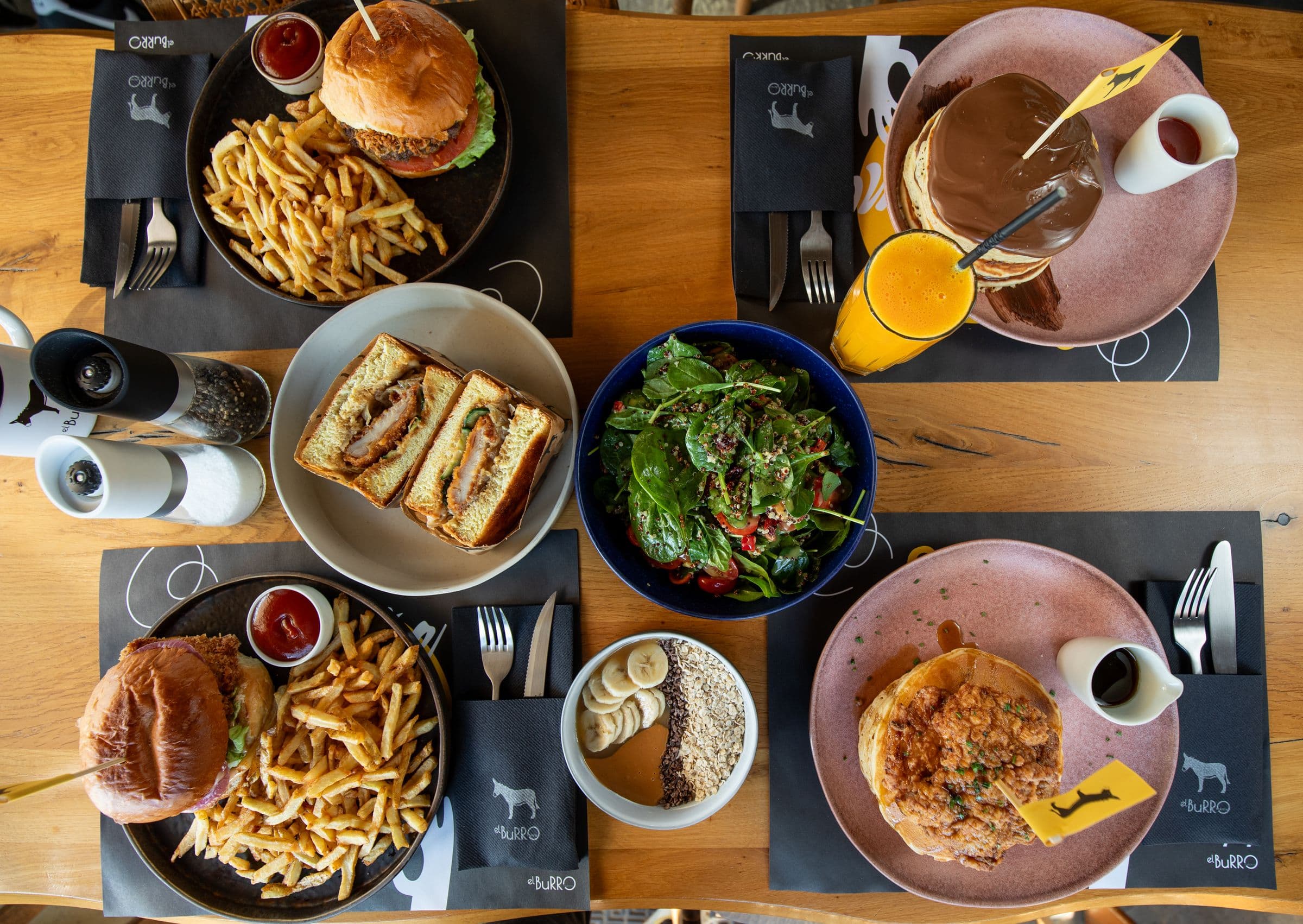 Brunch table from above: burgers, sando, pancakes, salads and fresh juice