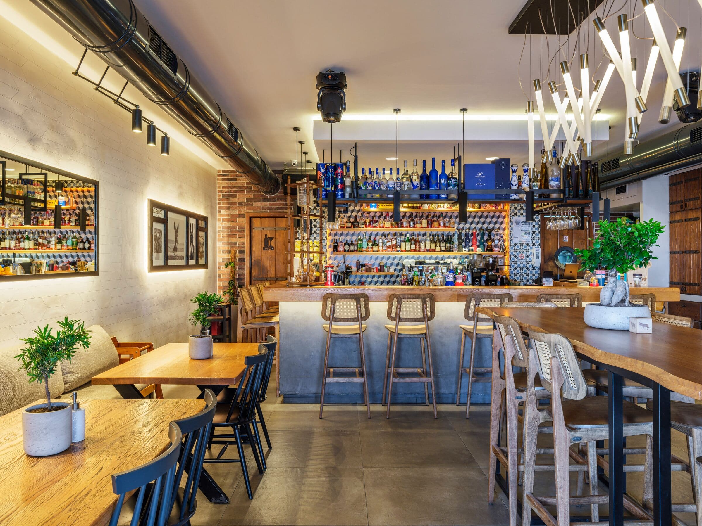 The bar and its bottle wall, seen past wooden tables and potted plants