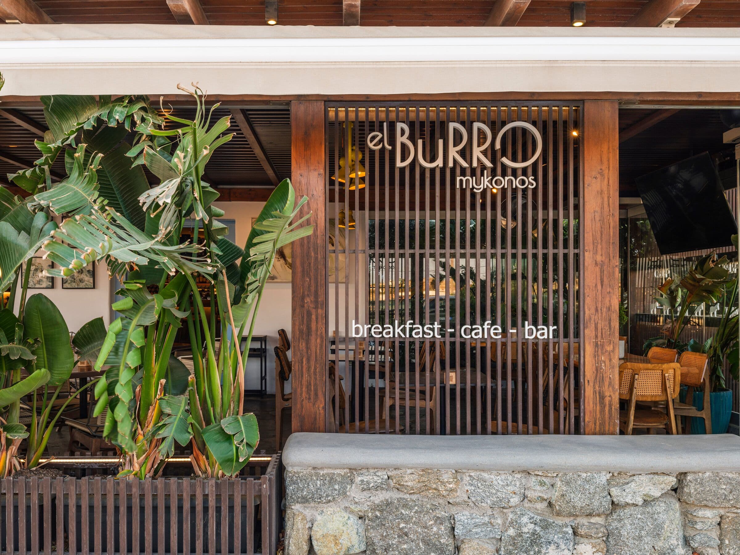The entrance: a slatted wooden door with the el BuRRO mykonos sign and the words breakfast, cafe, bar